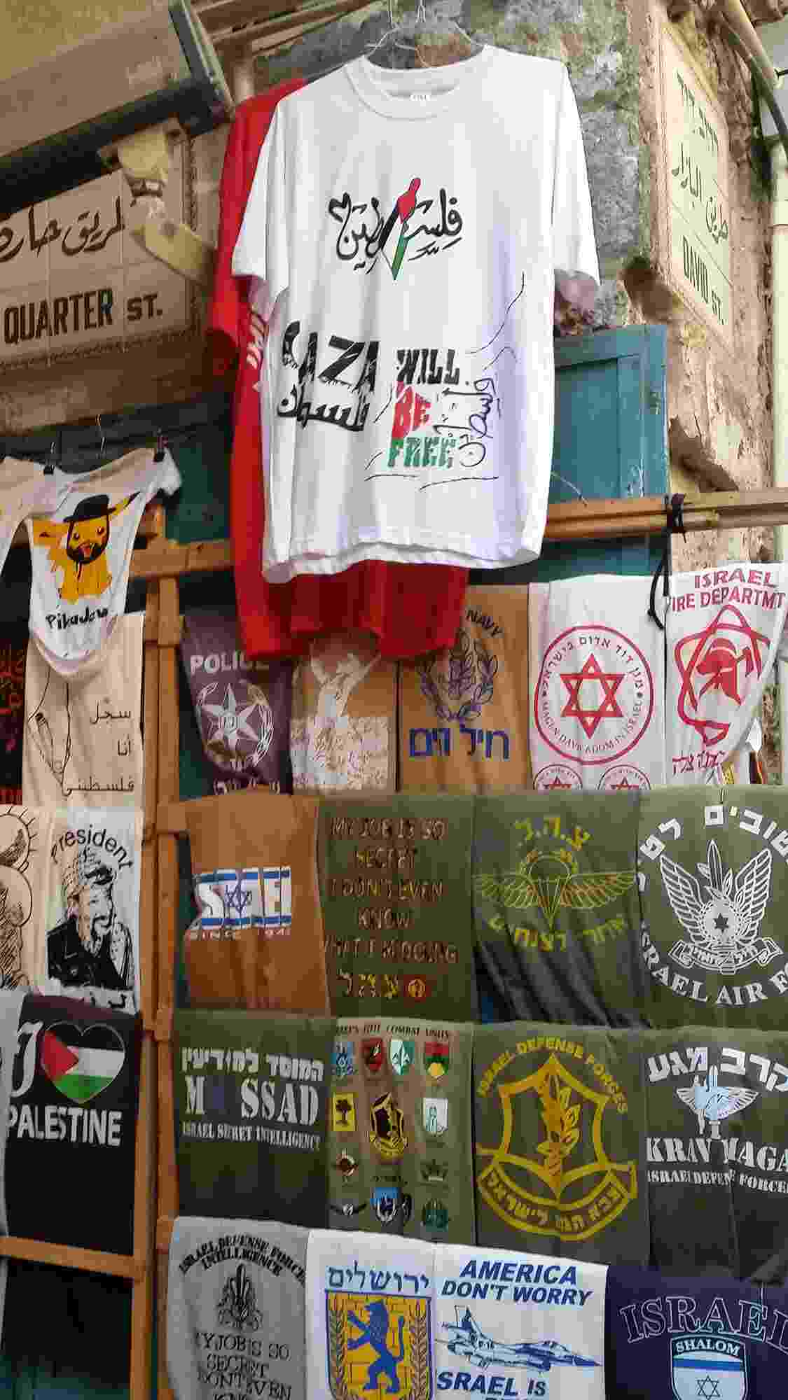 T-shirts hang from a wall and are displayed on wooden racks